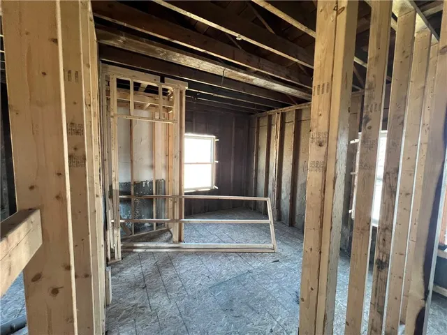 a view of an empty room with wooden floor and stairs