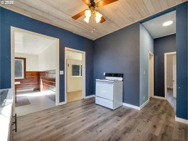 a view of a hallway with wooden floor and a kitchen