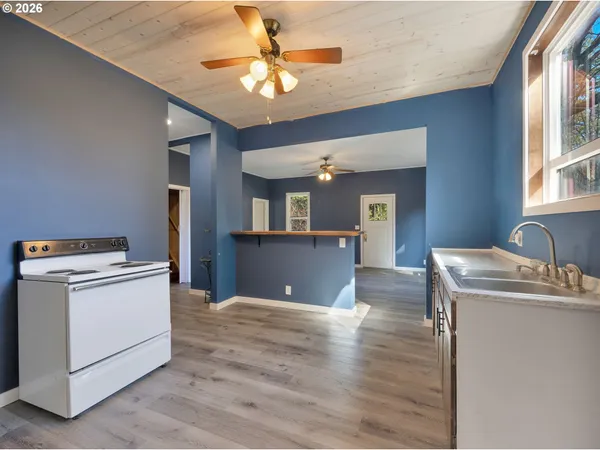 a view of kitchen with kitchen island a sink wooden floor and white appliances