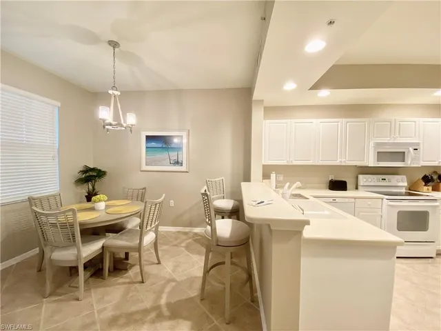 a kitchen with a dining table chairs and white appliances