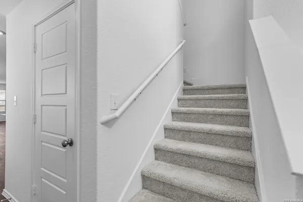 a view of staircase with white walls and white door