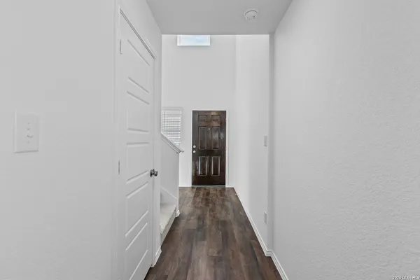 a view of a hallway with wooden floor and a bathroom