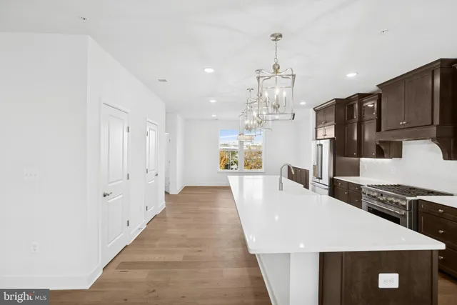 a large kitchen with sink a refrigerator and chairs