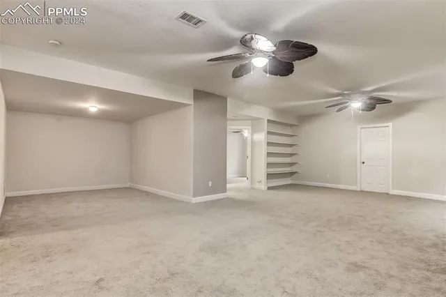 a view of an empty room with a chandelier fan