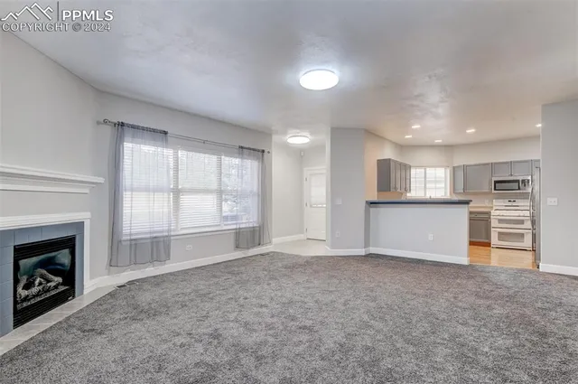 a view of an empty room with a window and fireplace