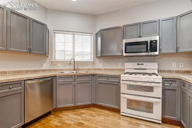 a kitchen with cabinets stainless steel appliances a sink and a window