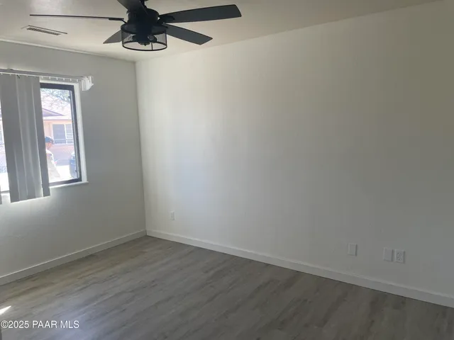 an empty room with a window and a ceiling fan