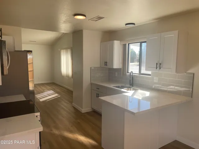 a view of a bathroom with granite countertop a sink and dishwasher with wooden floor