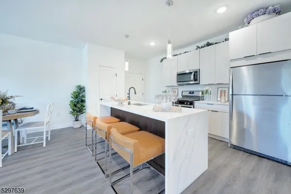a kitchen with stainless steel appliances white cabinets and wooden floor