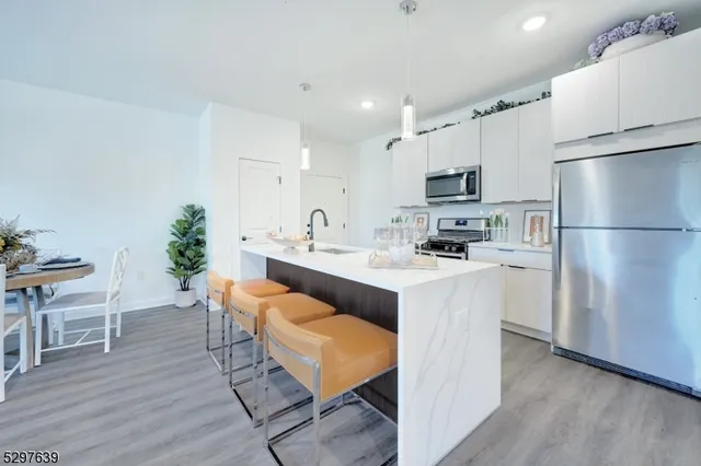a kitchen with stainless steel appliances white cabinets and wooden floor