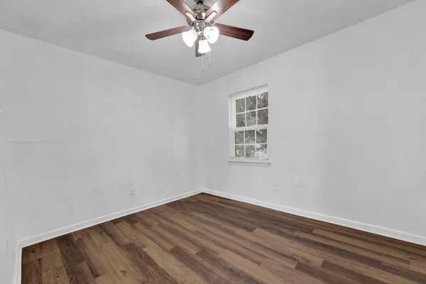 a view of a room with wooden floor and a ceiling fan