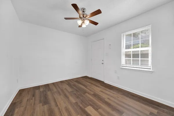 an empty room with wooden floor and ceiling fan