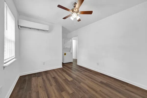a view of an empty room with window and wooden floor