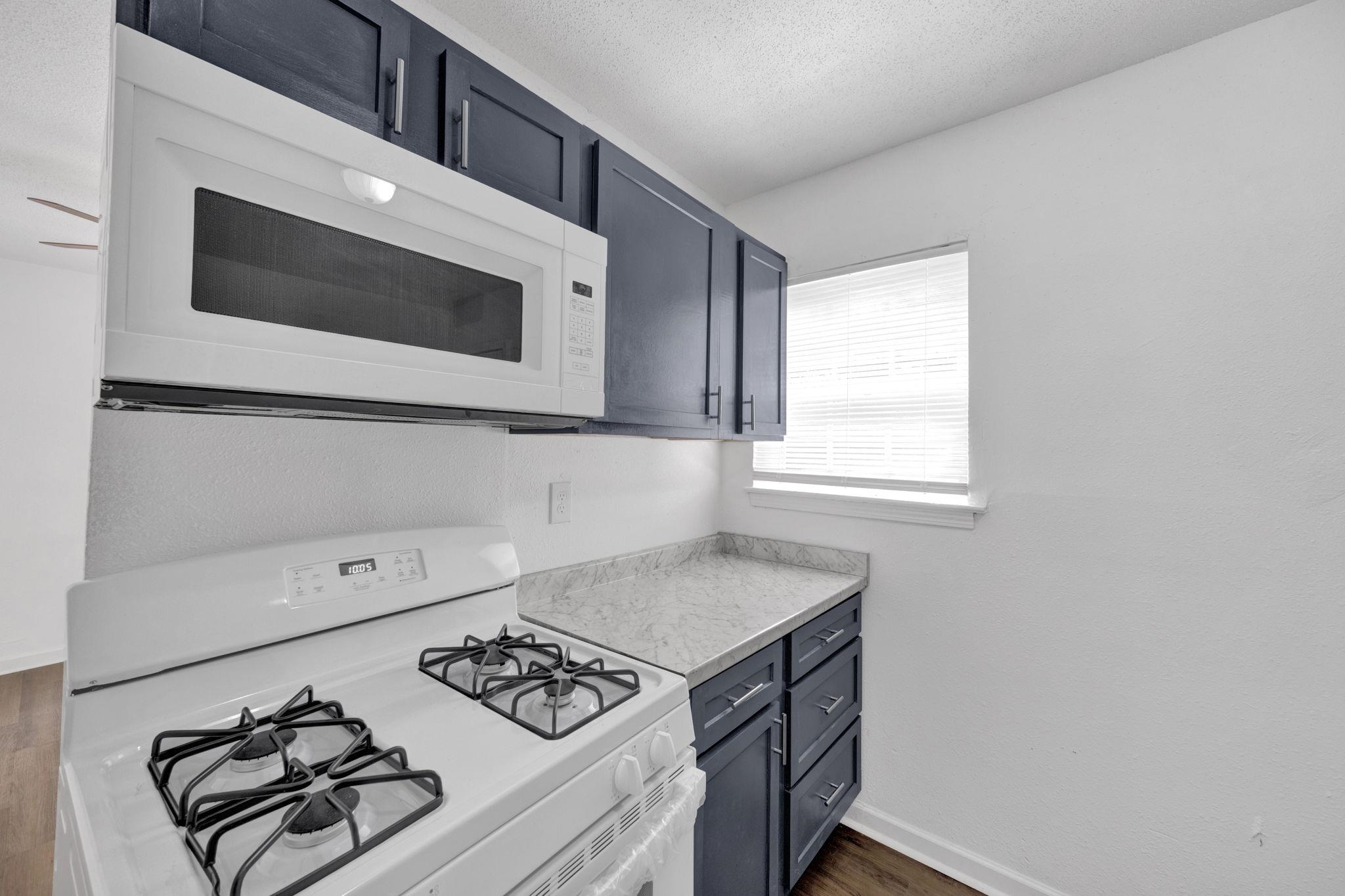 2966 Yale Avenue, Unit 3 Memphis, TN 38112 - Photo 6 of 24 Kitchen featuring white appliances, light countertops, a textured ceiling, dark wood finished floors, and blue cabinetry
