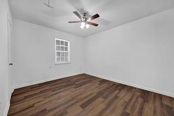 an empty room with wooden floor and ceiling fan