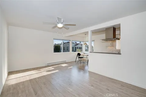 an empty room with wooden floor fan and windows