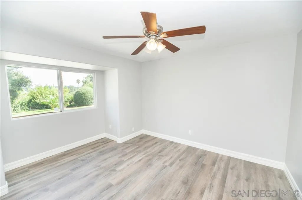 12841 Stone Canyon Road Poway, CA 92064 - Photo 14 of 25 an empty room with wooden floor fan and windows