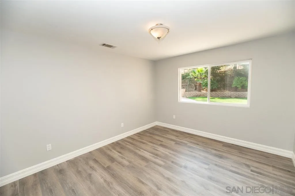 12841 Stone Canyon Road Poway, CA 92064 - Photo 17 of 25 an empty room with wooden floor and windows