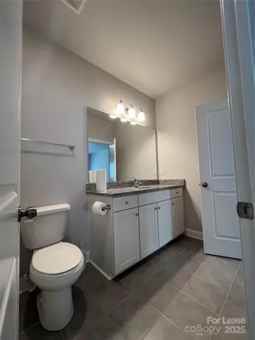 a bathroom with a toilet a sink a mirror and vanity