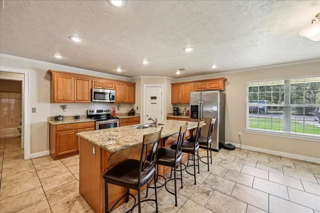 a open dining room with stainless steel appliances granite countertop a stove top oven a sink dishwasher a dining table and chairs with wooden floor