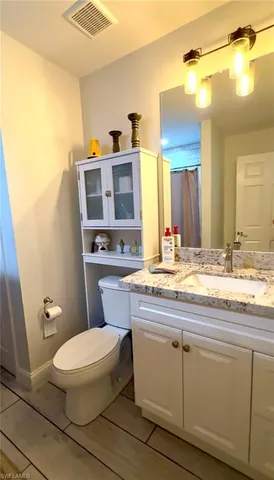 a bathroom with a granite countertop toilet sink and mirror