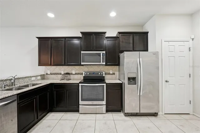 a kitchen with stainless steel appliances granite countertop a refrigerator and a sink