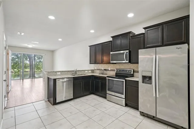 a large kitchen with stainless steel appliances granite countertop a refrigerator and a stove top oven
