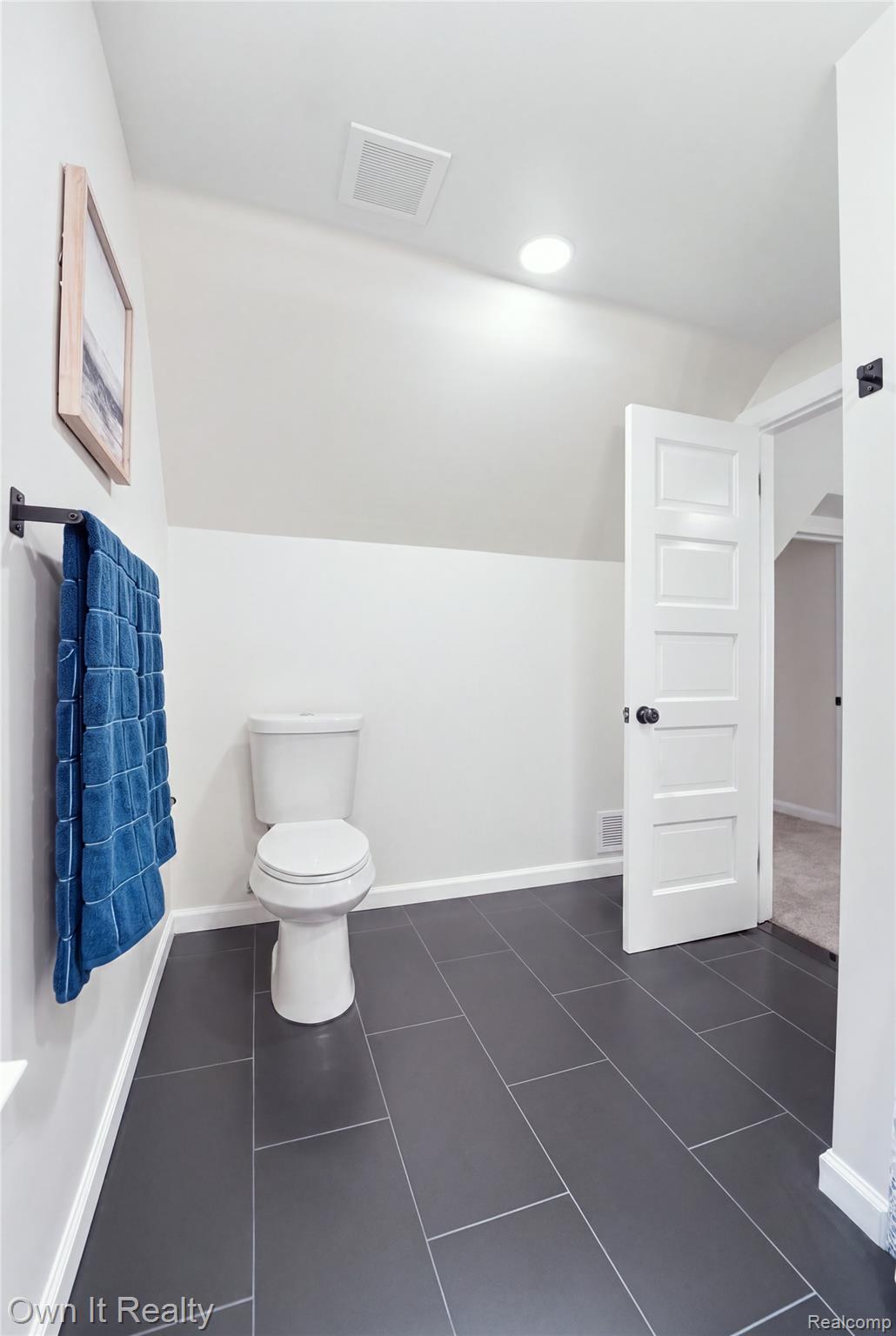 168 Kerby Road Grosse Pointe, MI 48236 - Photo 29 of 36 White-paneled door with black hardware, rectangular dark gray tile flooring, recessed ceiling light, and a sloped ceiling