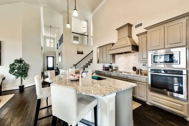 a kitchen with stainless steel appliances granite countertop a stove refrigerator and a fireplace with wooden floor