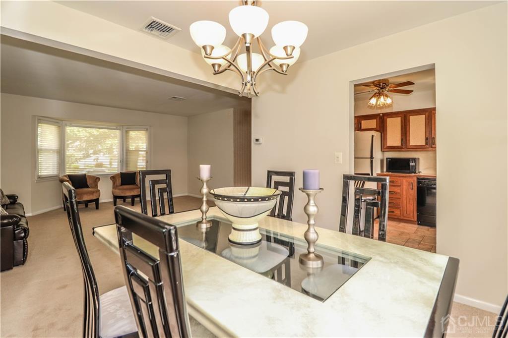 9 Meyer Road Edison, NJ 08817 - Photo 11 of 32 a dining room with wooden floor a chandelier a wooden table and chairs