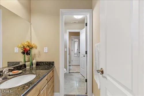 a bathroom with a granite countertop toilet and a sink