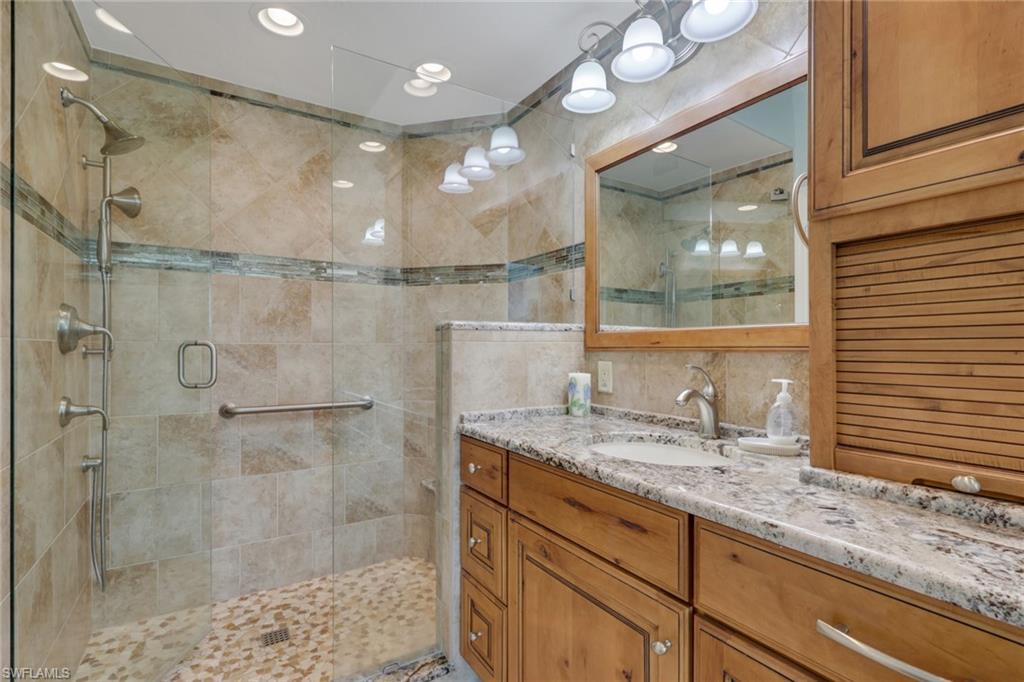 9281 Spring Run Boulevard, Unit 2607 Estero, FL 34135 - Photo 21 of 32 a bathroom with a granite countertop shower sink vanity and mirror