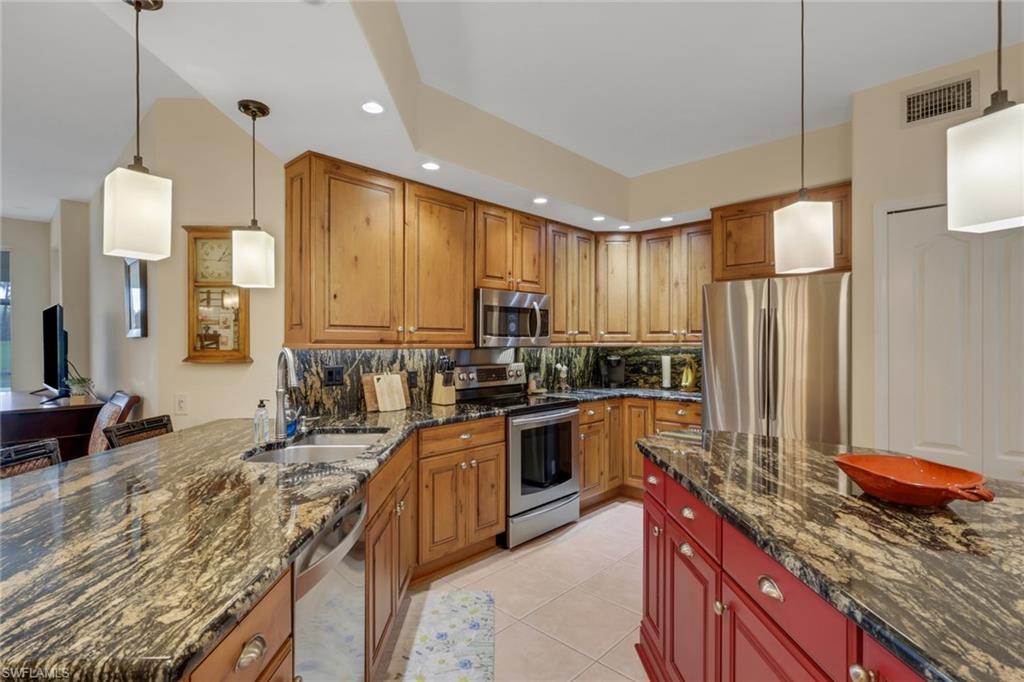9281 Spring Run Boulevard, Unit 2607 Estero, FL 34135 - Photo 8 of 32 a kitchen with stainless steel appliances granite countertop sink stove refrigerator and cabinets