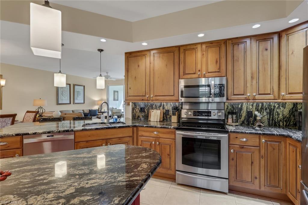 9281 Spring Run Boulevard, Unit 2607 Estero, FL 34135 - Photo 9 of 32 a kitchen with kitchen island granite countertop a stove sink and cabinets