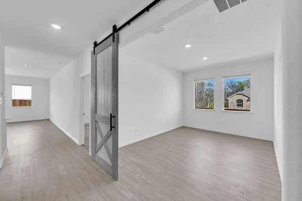 a view of an empty room with wooden floor and a window