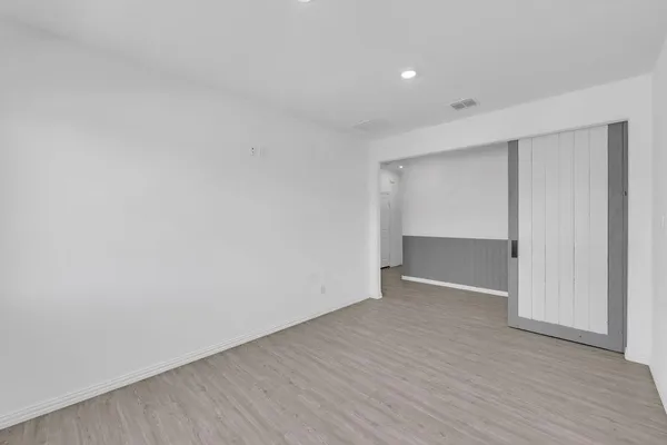 a view of an empty room with wooden floor and closet