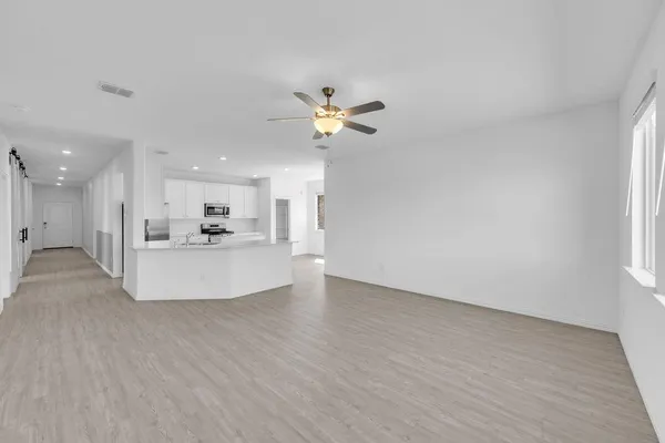 a view of a kitchen with a sink dishwasher a refrigerator with white cabinets and wooden floor