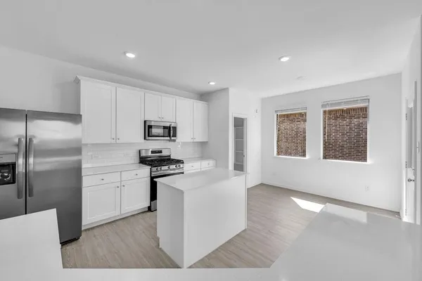 a kitchen with stainless steel appliances granite countertop a refrigerator a sink dishwasher a stove and white countertops with wooden floor