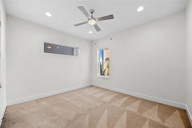 an empty room with a window and a ceiling fan