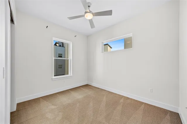 an empty room with chandelier fan and windows