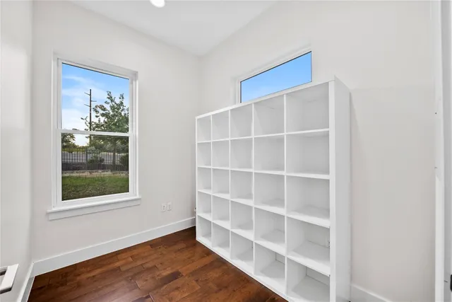 a view of an empty room with a window and wooden floor