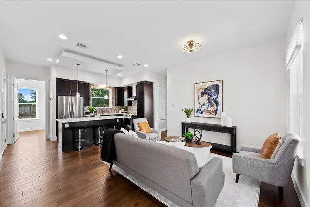 a living room with furniture and a dining table with wooden floor