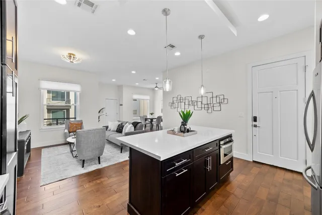 a kitchen with a stove a refrigerator and a dining table with wooden floor