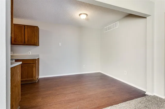 a view of an empty room with wooden floor and a fireplace