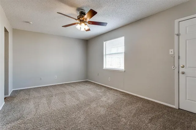an empty room with a chandelier fan and windows