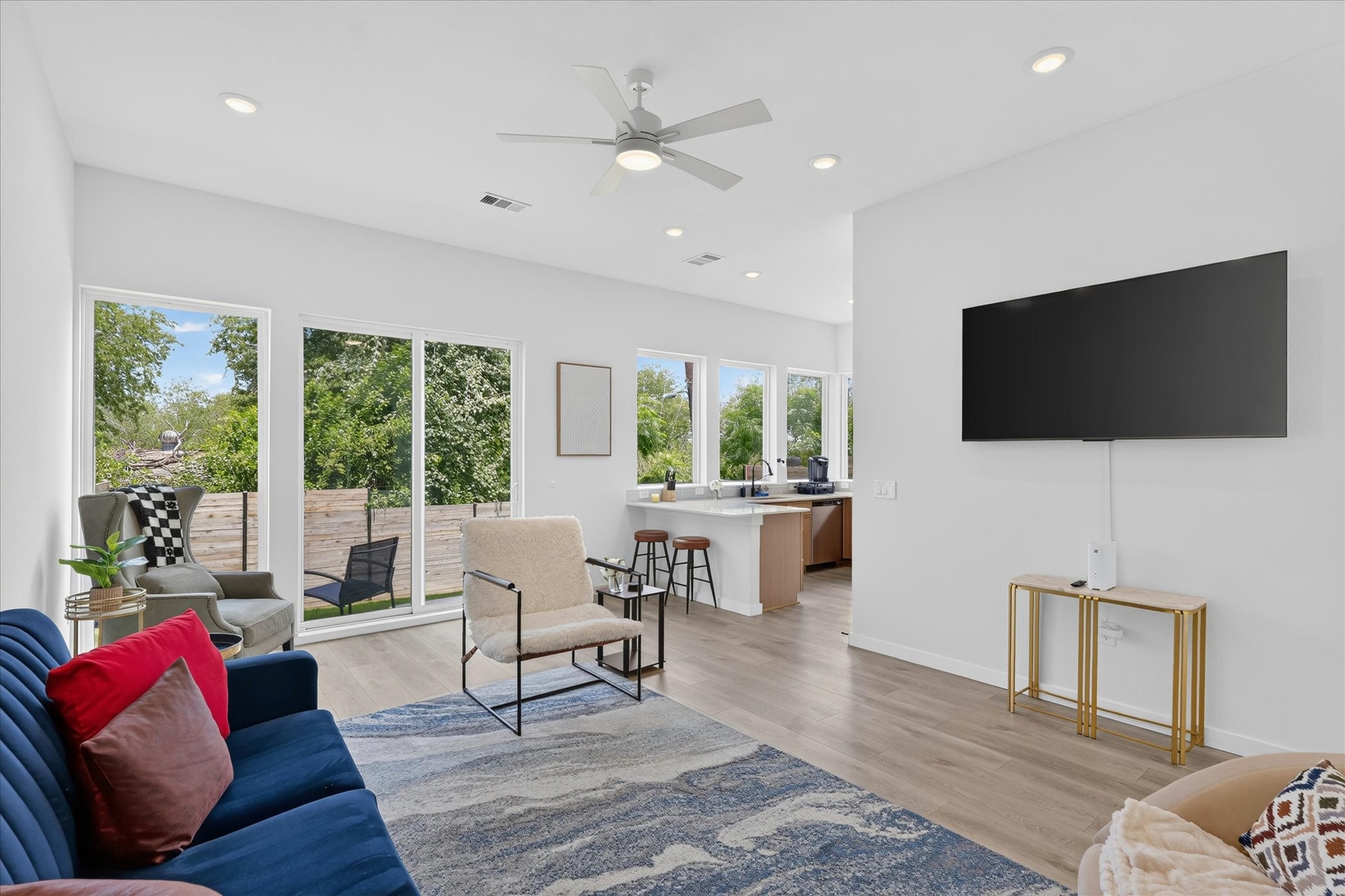 2000 Riverside Farms Road, Unit 8101 Austin, TX 78741 - Photo 5 of 41 Bright, open living space with modern decor, featuring large windows for natural light, a mounted TV, and access to a cozy outdoor area. The open layout connects to a kitchen with a breakfast bar, perfect for entertaining.