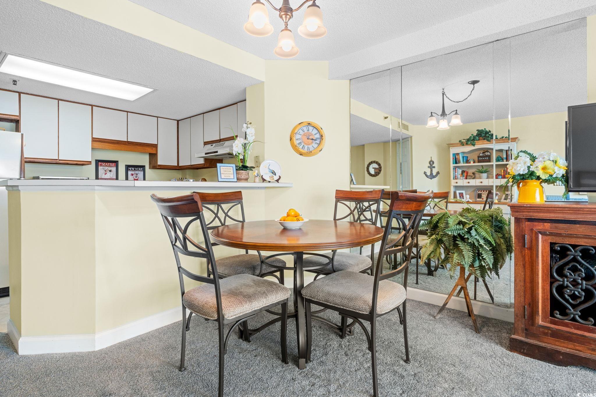 5511 North Ocean Boulevard, Unit 208 Myrtle Beach, SC 29577 - Photo 11 of 37 Dining room with a chandelier, light colored carpet, and a textured ceiling