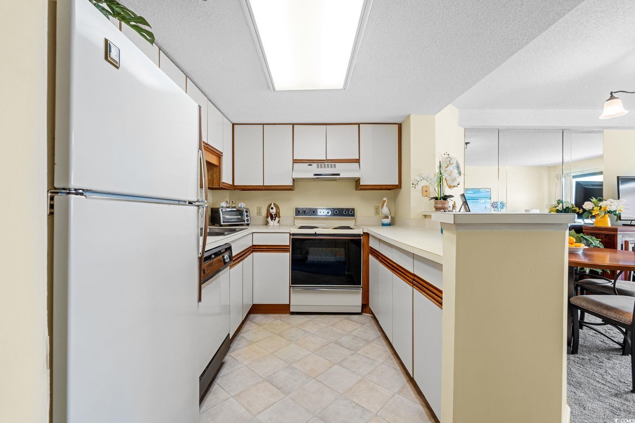 5511 North Ocean Boulevard, Unit 208 Myrtle Beach, SC 29577 - Photo 13 of 37 Kitchen with white appliances, white cabinets, light countertops, a textured ceiling, and brown cabinets