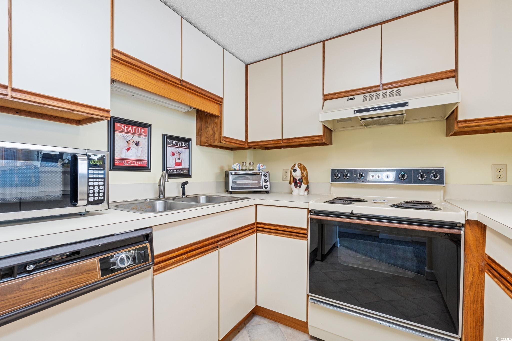 5511 North Ocean Boulevard, Unit 208 Myrtle Beach, SC 29577 - Photo 14 of 37 Kitchen featuring white appliances, white cabinetry, light countertops, exhaust hood, and brown cabinetry