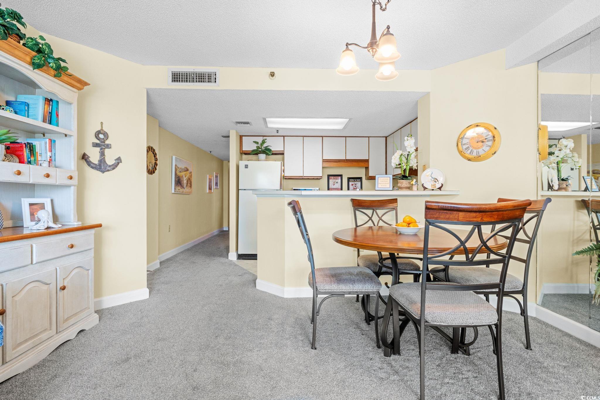 5511 North Ocean Boulevard, Unit 208 Myrtle Beach, SC 29577 - Photo 10 of 37 Dining room with light carpet, a chandelier, and a textured ceiling
